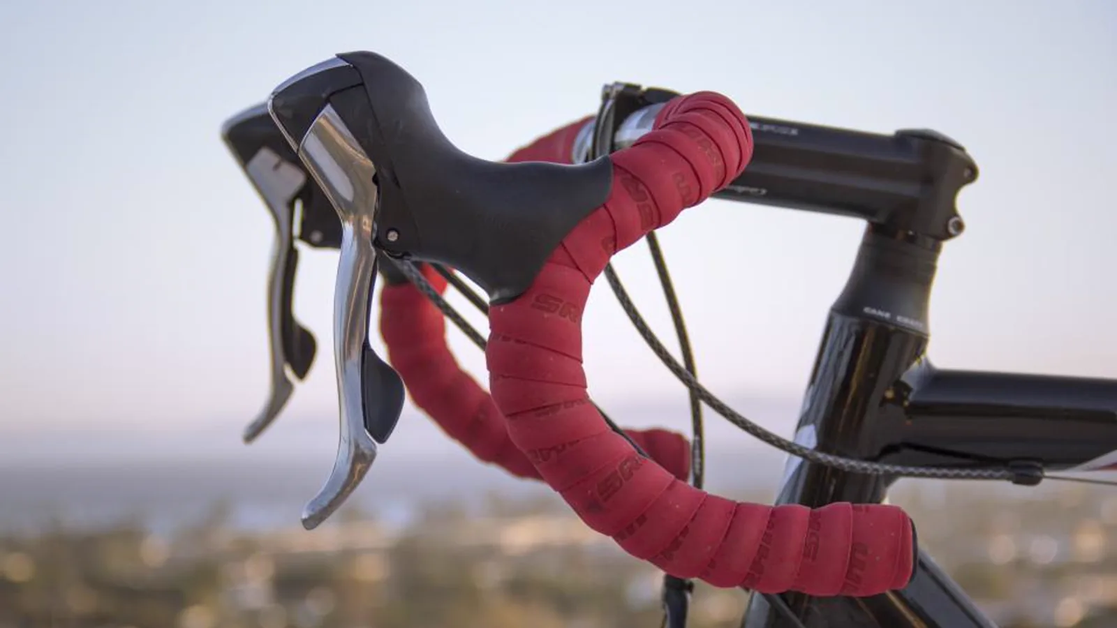 Rennrad-Cockpit mit rotem Lenkerband vor Abendhimmel